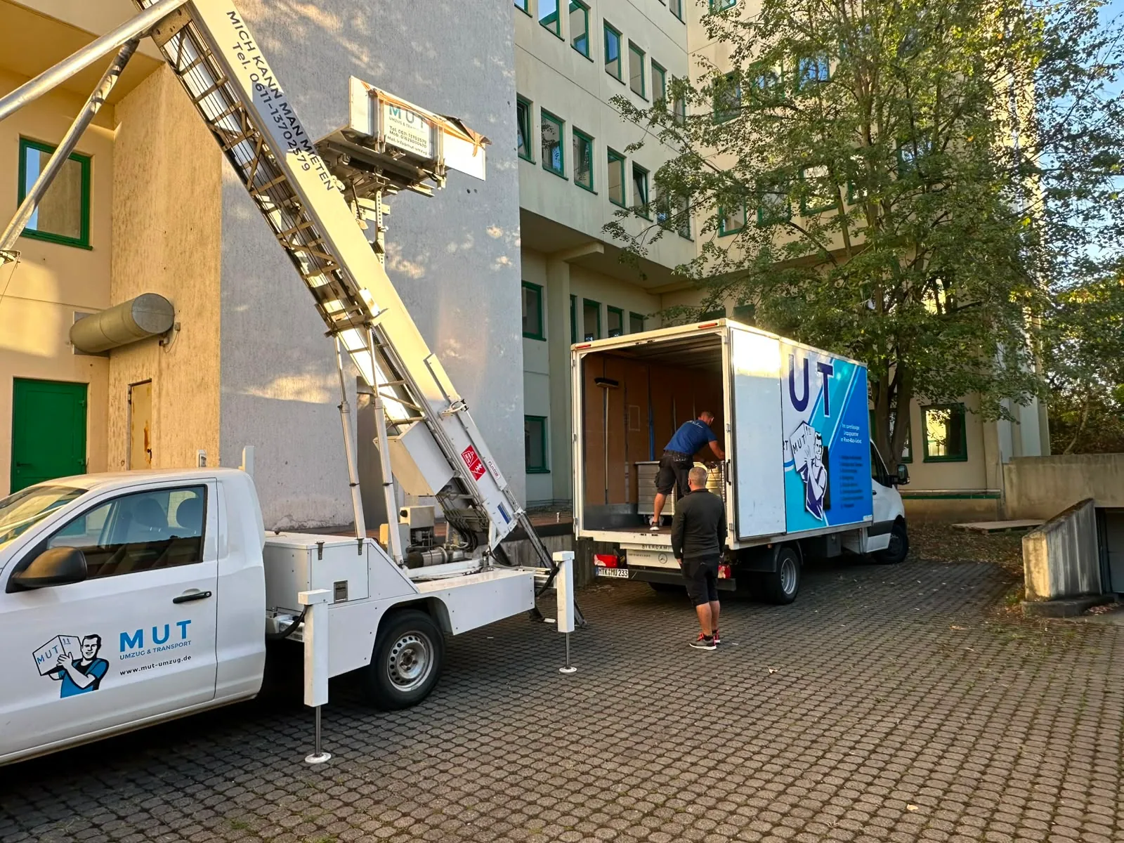 Möbellift an einem Altbau, daneben der MUT-Umzugswagen beim Beladen
