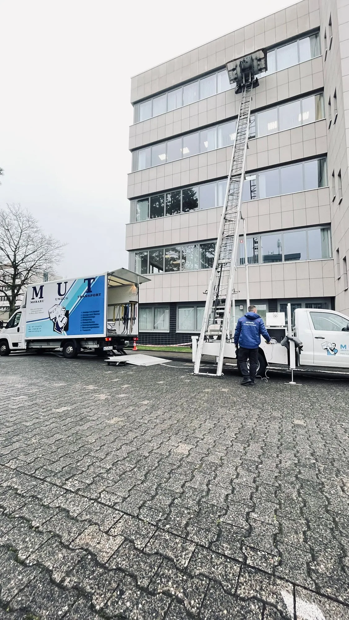 Möbellift an einem Bürogebäude, davor ein MUT-Umzugswagen