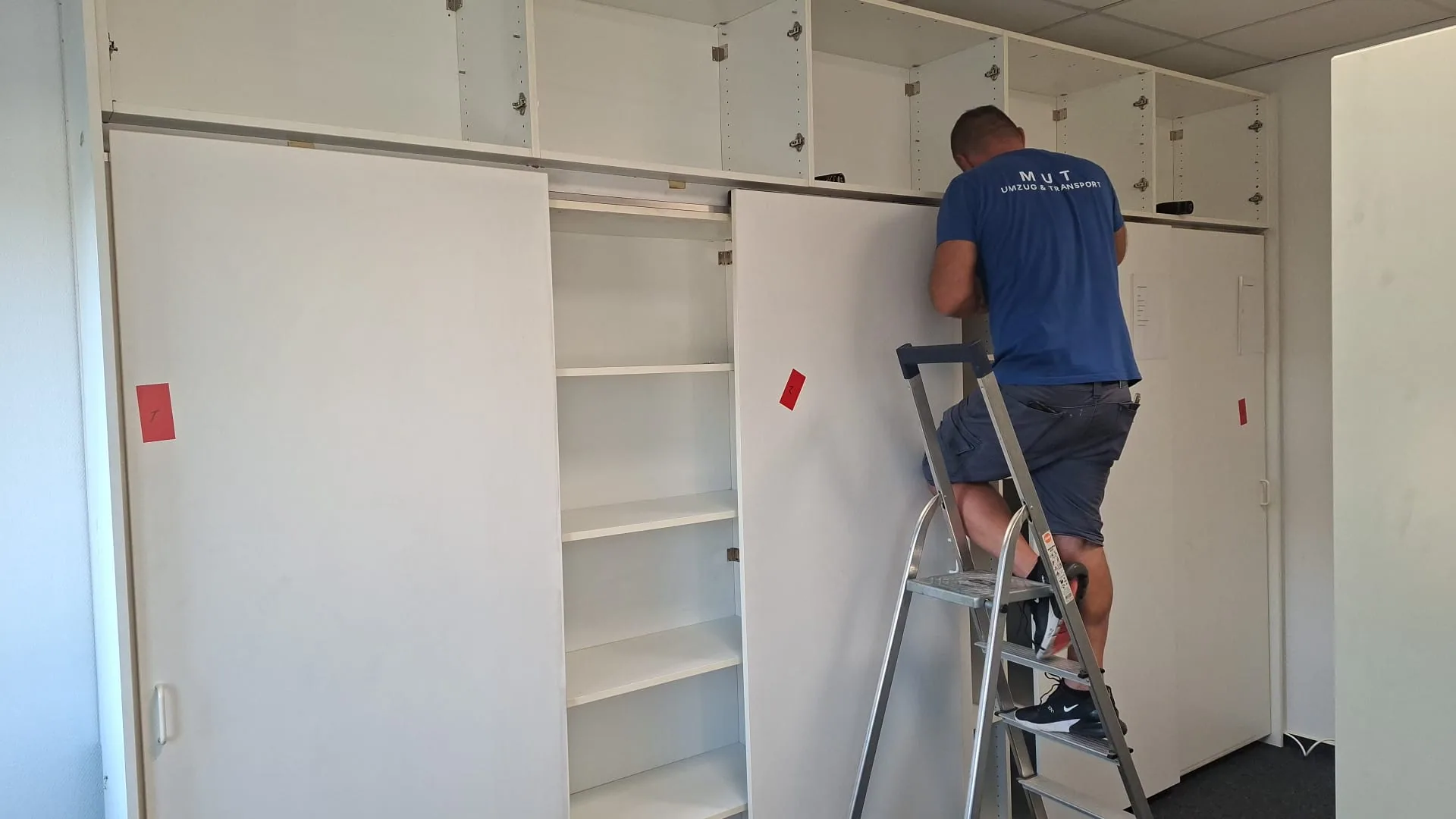 MUT-Mitarbeiter baut einen Einbauschrank in einem Büro ab, die Teile sind nummeriert