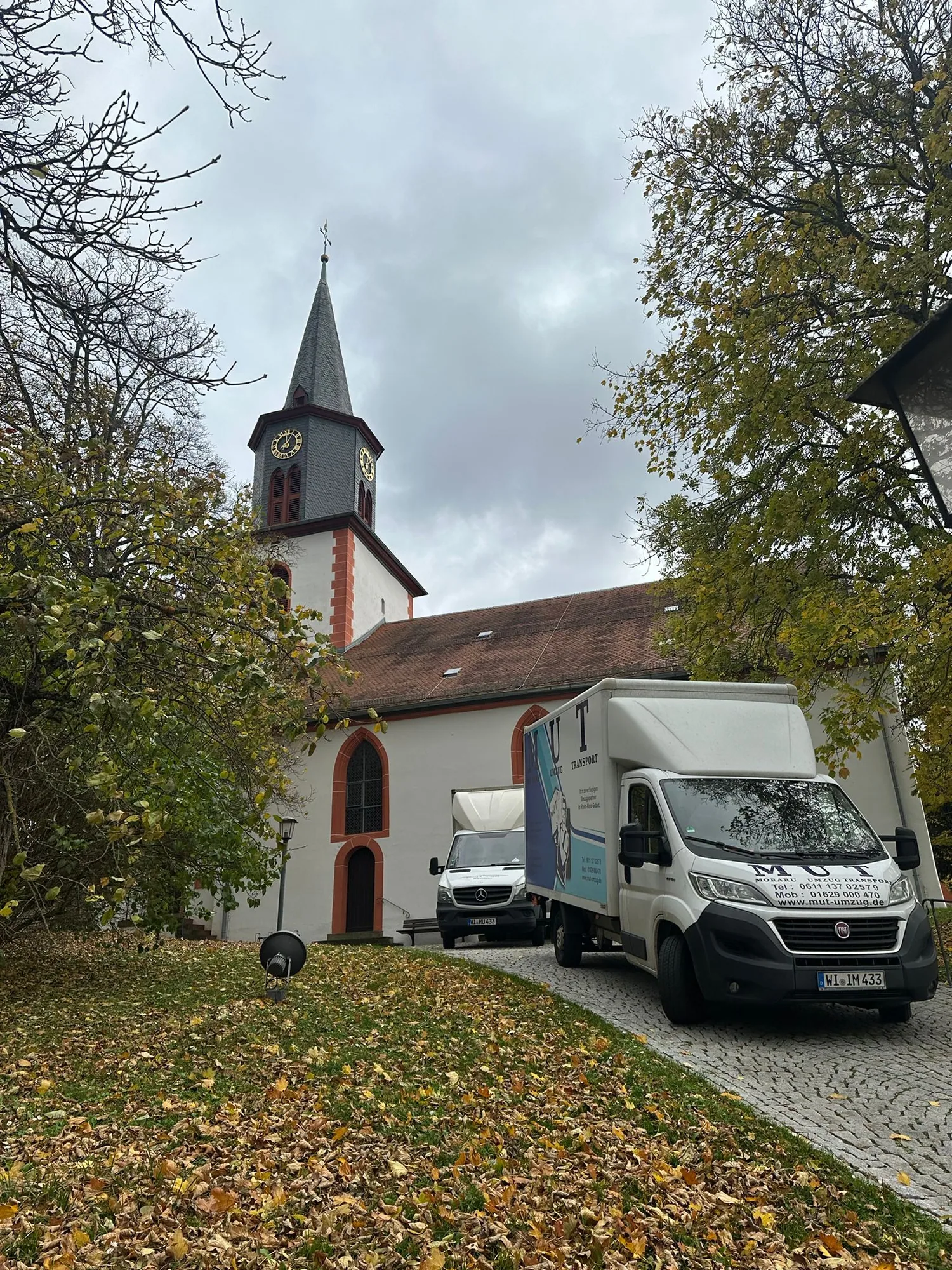 MUT-Umzugswagen vor einer Kirche im Herbst