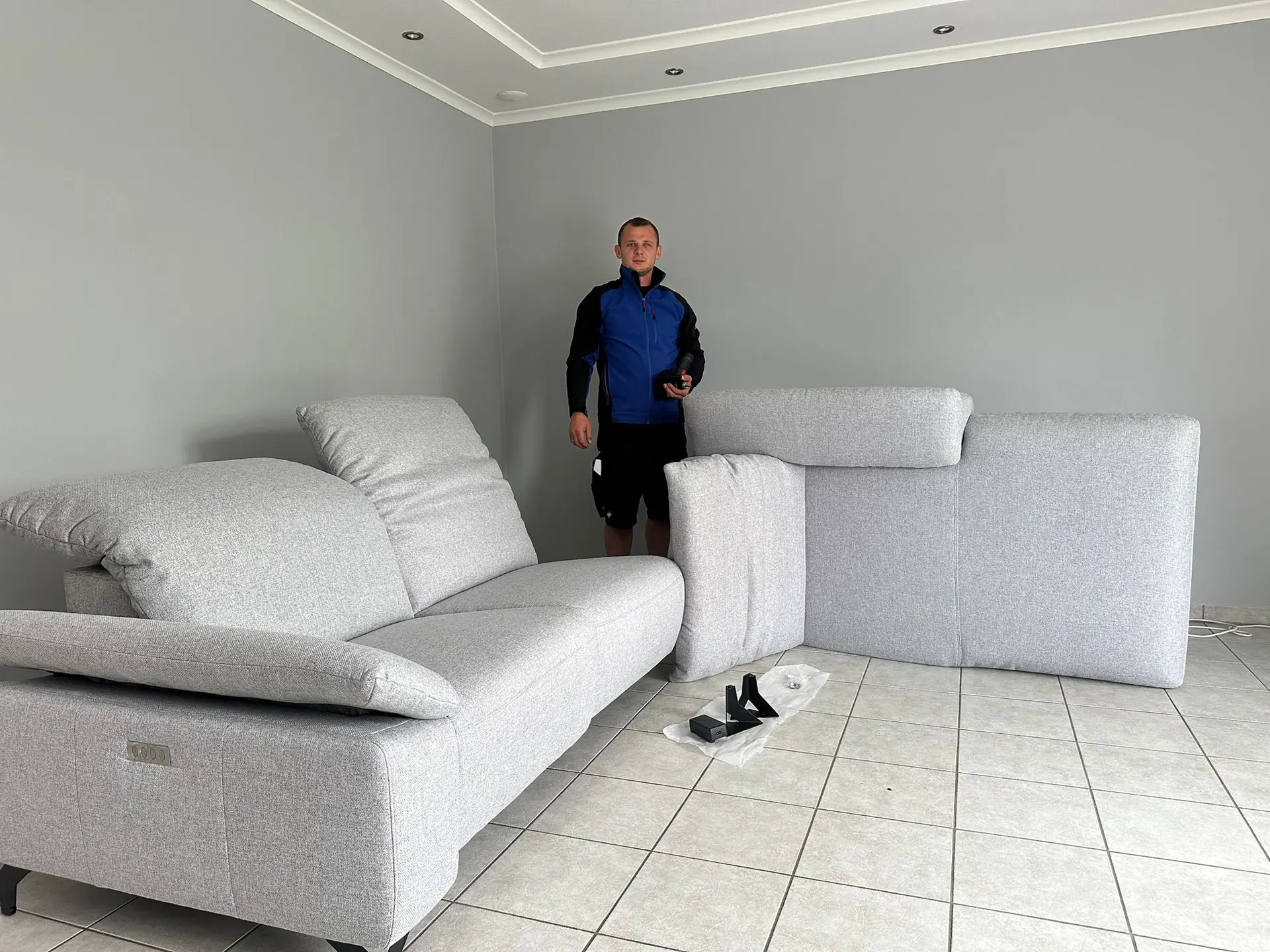 MUT-Mitarbeiter neben einem fertig aufgebauten Sofa